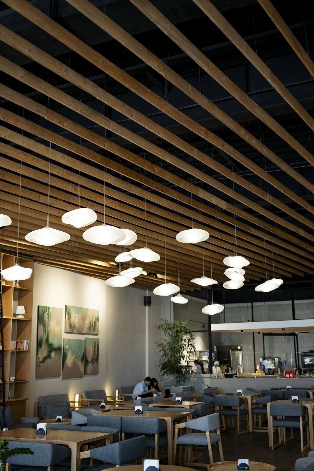 Restaurante con techo de lamas de madera, lámparas colgantes y mesas