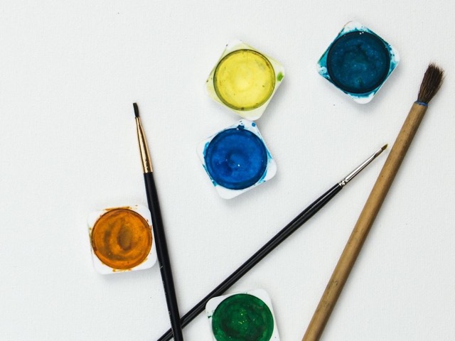 Pastillas de acuarela de colores y tres pinceles sobre papel blanco