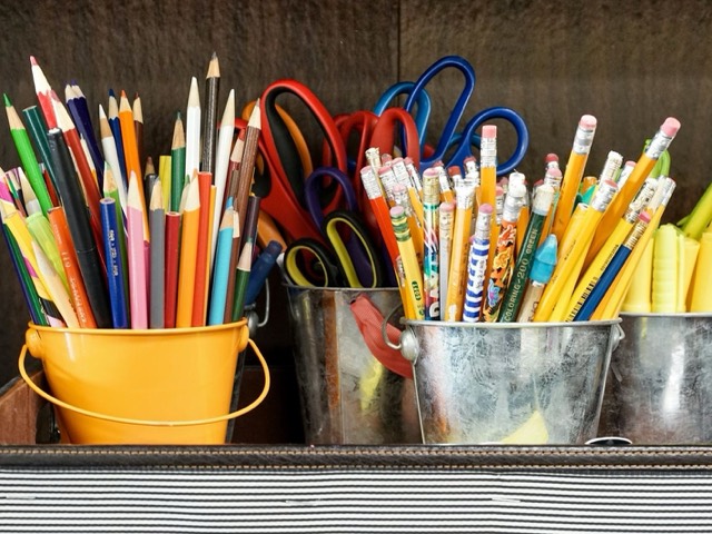 Lápices de colores, lápices de grafito y tijeras en cubos de metal