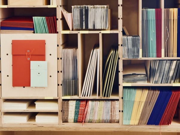 Estantería de madera con sobres, carpetas y papel de colores